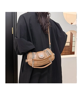 Detail of brown pebbled leather crossbody bag with silver chain and twist-lock on a model
