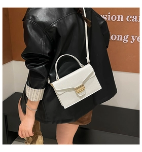Détail d'un sac à main blanc motif litchi avec fermoir doré porté par un mannequin