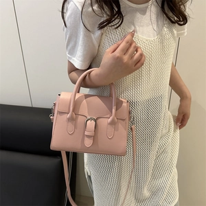 Pink faux leather shoulder bag with top handle and silver buckle worn by a model