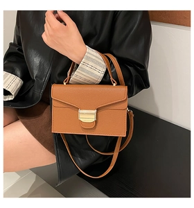 Détail du sac à main marron en cuir grainé avec fermoir doré et poignée élégante