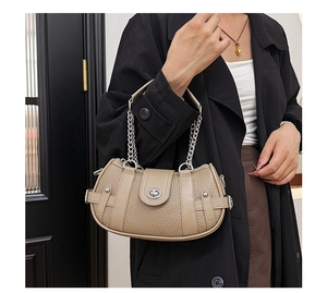 Detail of khaki crescent leather bag featuring silver studs and metal twist lock