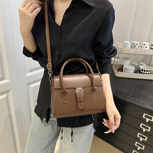 Chic brown leather crossbody bag with silver buckle worn by a model in a modern interior