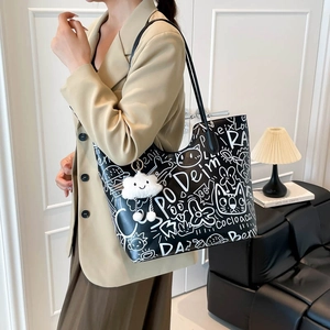 Fashionable black tote bag with white graffiti prints and a cloud charm on shoulder