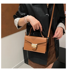 Mini sac marron en cuir grainé avec boucle dorée porté en bandoulière par un mannequin