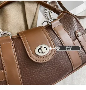 Close-up of vintage brown leather handbag featuring a metallic silver hardware twist lock