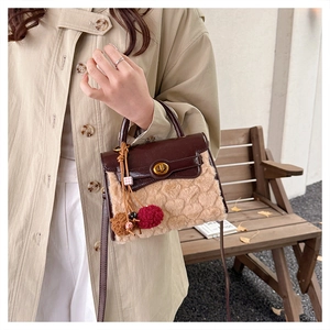 Detail of lamb wool handbag with heart texture, leather handle, and gold twist lock