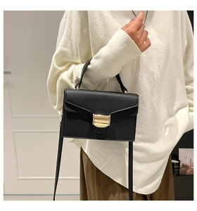 Détail d'un sac à main en cuir grainé noir avec boucle dorée et bandoulière