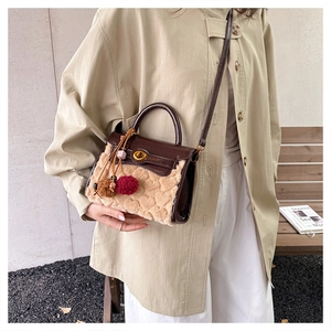 Detail view of the plush shearling and brown faux leather handbag with golden lock