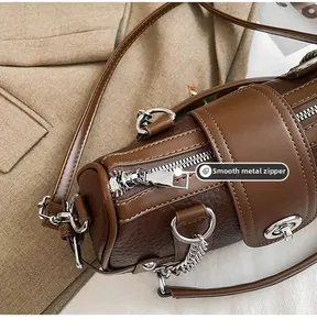 Detail of silver smooth metal zipper and lychee leather texture on a brown barrel bag