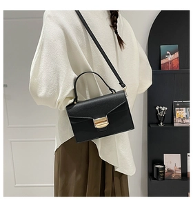Détail du sac à main en cuir grainé noir avec boucle dorée et bandoulière réglable