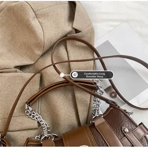 Detail showing the adjustable long leather shoulder strap on a brown patchwork handbag