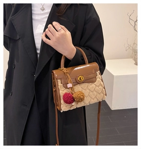 Detail of brown leather handbag with beige textured fur panels and golden swivel lock