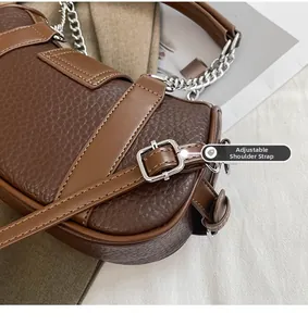 Detail of lychee textured leather crossbody bag with silver chain and adjustable strap