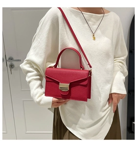 Détail du sac à main rouge à motif litchi avec boucle dorée et bandoulière réglable