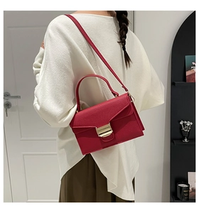 Détail du sac à main en cuir rouge grainé avec fermoir doré et bandoulière fine