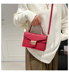 Détail du sac à main en cuir grainé rouge avec boucle dorée et bandoulière réglable