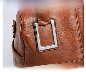 Close-up of brown pebbled leather texture and silver rectangular metal buckle on tote bag
