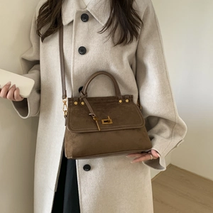 Sac à main rétro en daim marron avec boucle dorée porté en bandoulière pour un look chic