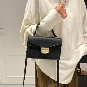 Sac à main chic en cuir noir à motif litchi avec boucle dorée dans un cadre élégant