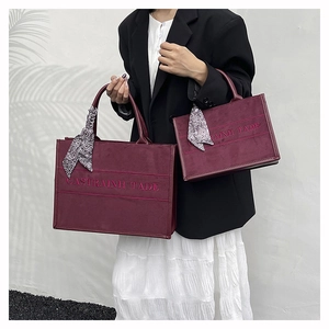 Macro shot of two burgundy velvet tote bags with silk scarves and pink embroidery