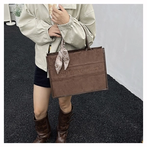 Brown suede tote bag detail featuring patterned silk scarf and embossed text detail