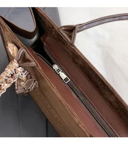 Detail of premium hardware zipper on brown suede tote bag with decorative silk scarf