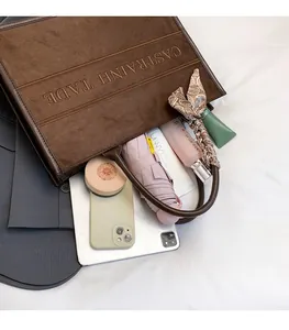 Brown frosted tote bag showing interior space with a phone, tablet, and cosmetics