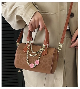 Detail of vintage leopard print Boston bag with gold hardware and strawberry chain accessory