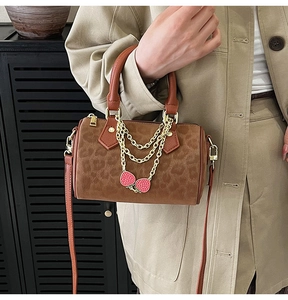 Detail of brown leopard print Boston bag with gold chains and red strawberry charms