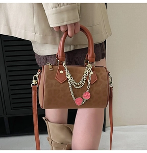 Close-up of leopard print Boston bag with gold chains and strawberry pendants