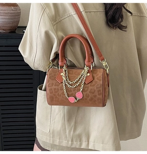 Detail of vintage leopard print Boston bag with golden chains and strawberry charm