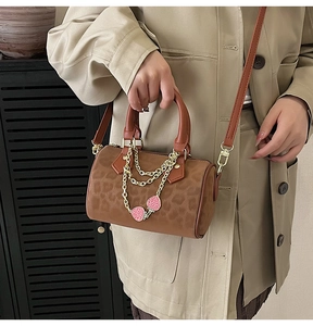 Detail of leopard print Boston bag featuring gold chains and pink strawberry charms