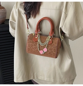 Detail of leopard print Boston bag with gold chain and pink strawberry charms on strap