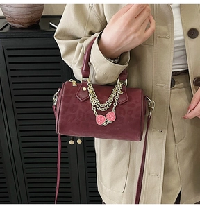 Detail of vintage burgundy leopard embossed boston bag with golden chain and strawberry charm