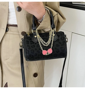 Detail of leopard print Boston bag with gold chain and strawberry charm on shoulder