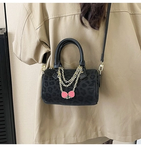 Detail of leopard print Boston bag with gold chains and strawberry charm on model