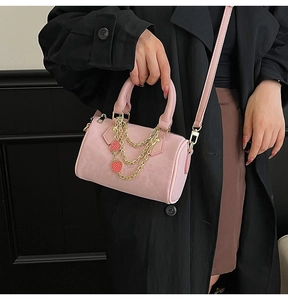 Detail of pink leopard Boston bag with gold chains and strawberry charms worn by model