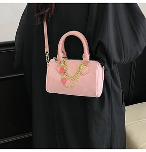 Pink boston bag with gold chains and strawberry charms shown on a model's arm
