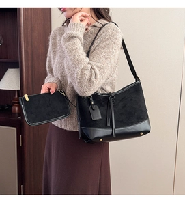 Detail of black suede patchwork tote and clutch set with gold hardware on model