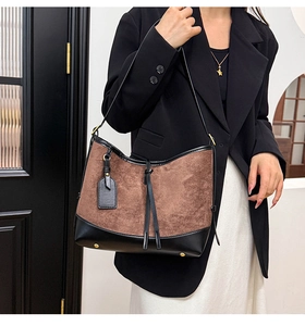 Detail of suede and leather patchwork tote featuring gold feet and vintage design