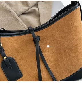 Detailed close-up of brown suede tote bag with black leather stitching and decorative strap