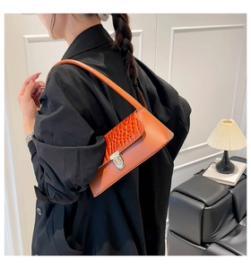 Detail of orange crocodile embossed faux leather shoulder bag with silver buckle