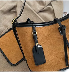 Detail view of brown matte suede tote with black leather trim and gold hardware accents