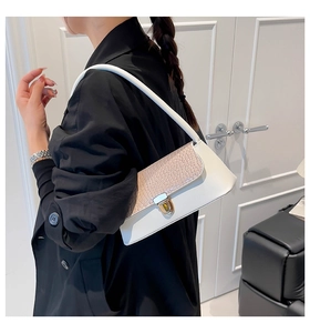 Detail of white leather shoulder bag with pink croc-texture flap and golden buckle