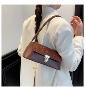 Close-up of brown baguette bag with crocodile pattern and silver metal swivel lock