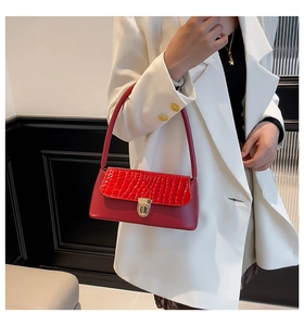 Detail of red baguette bag with crocodile pattern flap and golden twist-lock closure