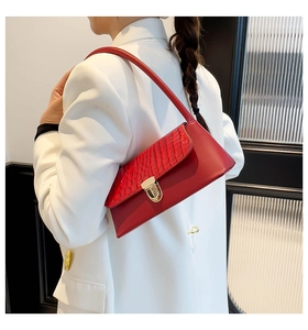 Detail of red croc-embossed leather shoulder bag with elegant gold metal buckle