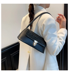 Detail of black underarm bag featuring crocodile embossed flap and gold metal buckle