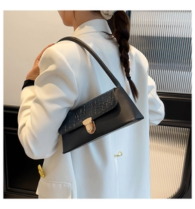 Detail of black baguette bag featuring crocodile pattern texture and gold metal buckle