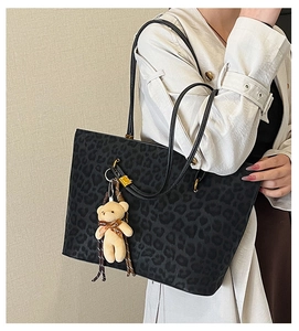 Close-up of black leopard print tote bag with golden hardware and cute bear charm